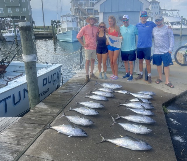 NC fishing party with their catch of yellowfin and blackfin tuna and holding a sailfish release flag