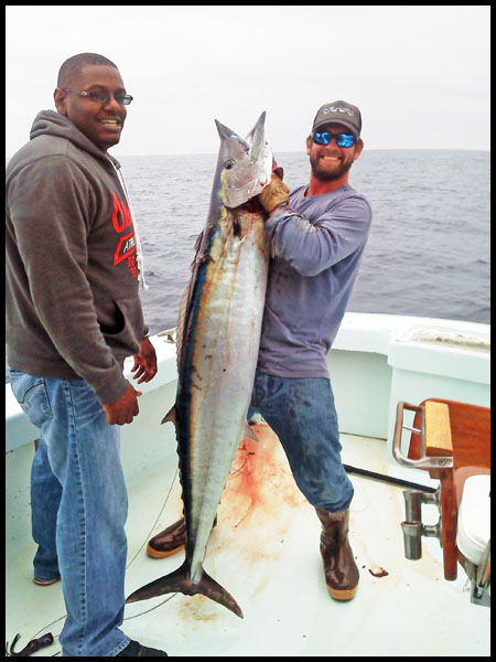 angler and mate holding up a very fat wahoo